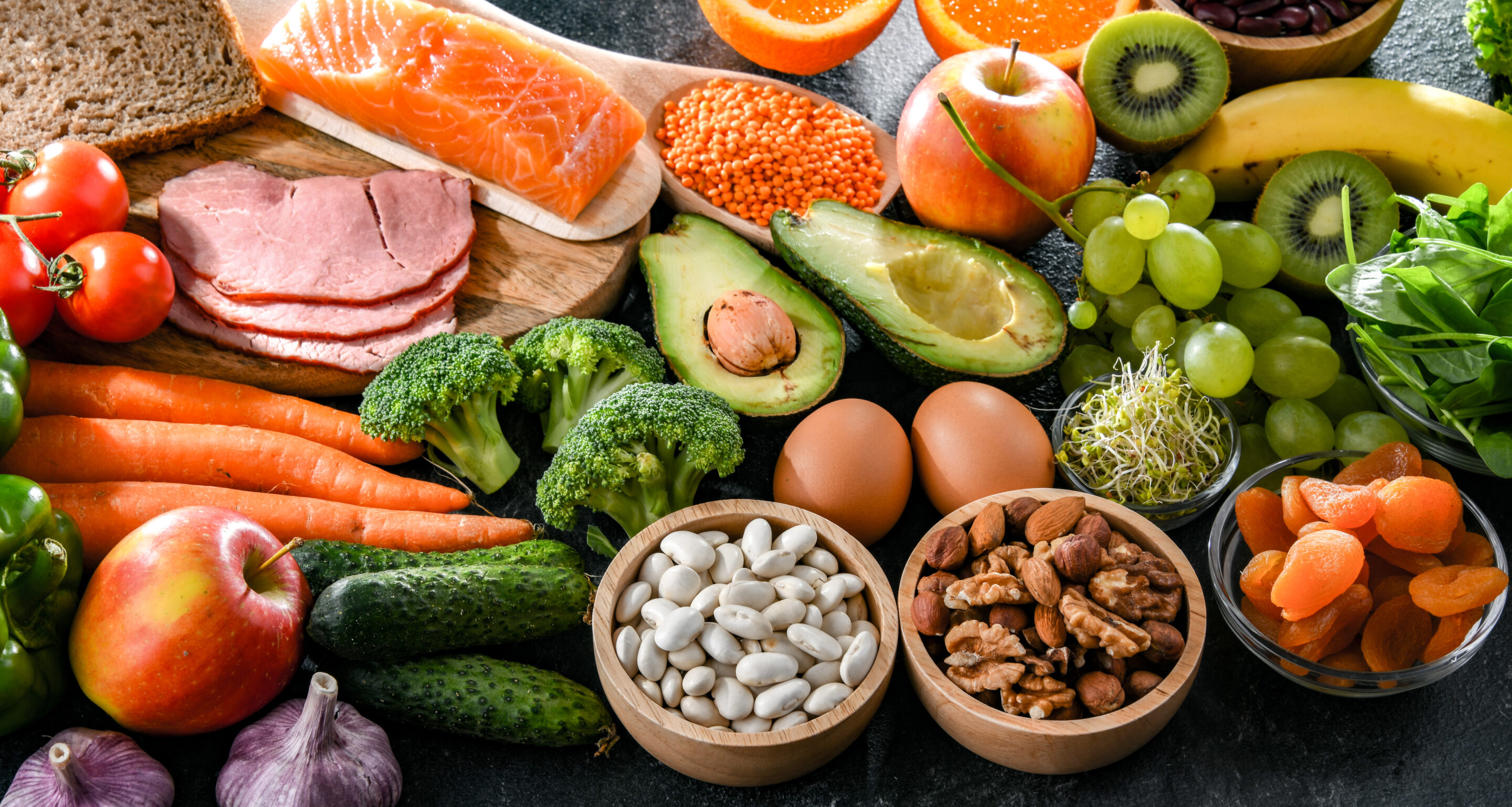 Verschiedene Lebensmittel, wie Obst, Gemüse, Nüsse, Fleisch verteilt auf den Tisch.