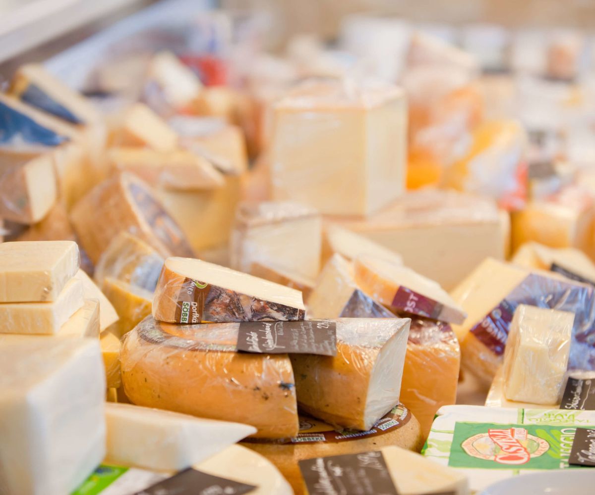 Auswahl an Bio-Käse an der Theke, verschiedene Sorten angeschnitten und verpackt.